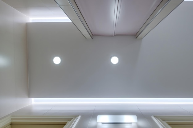 Foto soffitto sospeso con lampade alogene e costruzione di cartongesso in una stanza vuota in appartamento appartamento ufficio clinica hotel o casa soffitto teso bianco e forma complessa