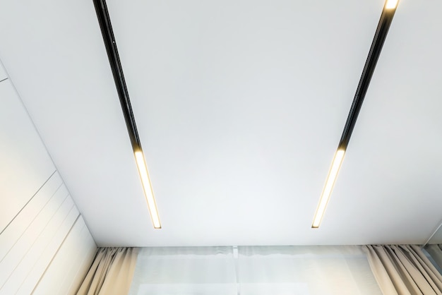 Suspended ceiling with halogen spots lamps and drywall construction in empty room in apartment or house Stretch ceiling white and complex shape