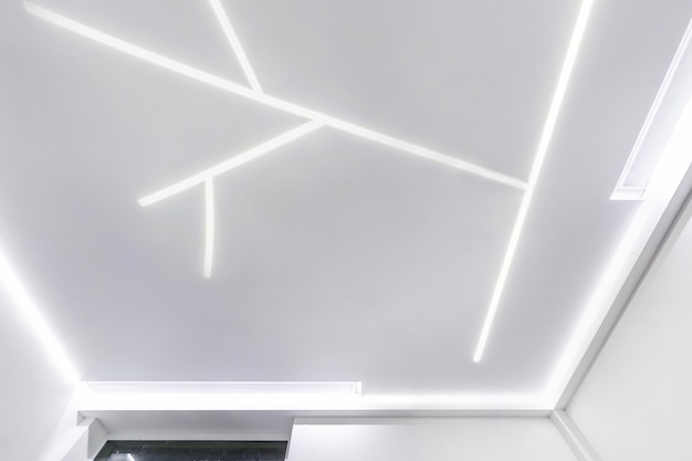 Suspended ceiling with halogen spots lamps and drywall construction in empty room in apartment or house Stretch ceiling white and complex shape