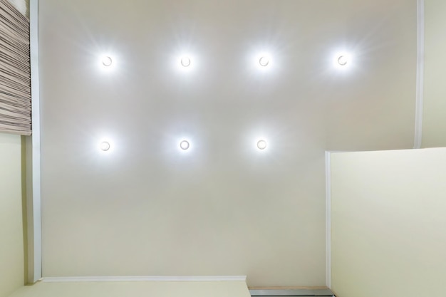 Suspended ceiling with led lightspot lamps and drywall construction in empty room in apartment or house Stretch ceiling white and complex shape looking up