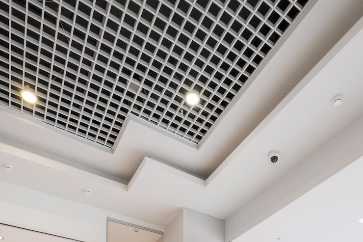 Photo suspended and grid ceiling with halogen spots lamps and drywall construction in empty room in store or house stretch ceiling white and complex shape