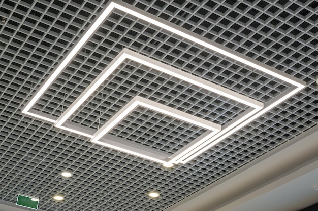 Suspended and grid ceiling with halogen spots lamps and drywall construction in empty room in store or house Stretch ceiling white and complex shape