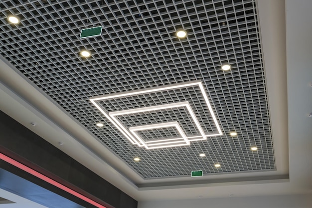 Suspended and grid ceiling with halogen spots lamps and drywall\
construction in empty room in store or house stretch ceiling white\
and complex shape