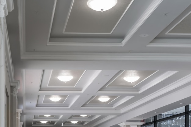 Suspended and grid ceiling with halogen spots lamps and drywall\
construction in empty room in store or house stretch ceiling white\
and complex shape