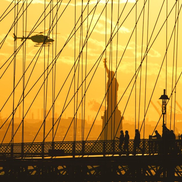 Photo suspension bridge in city against sky during sunset