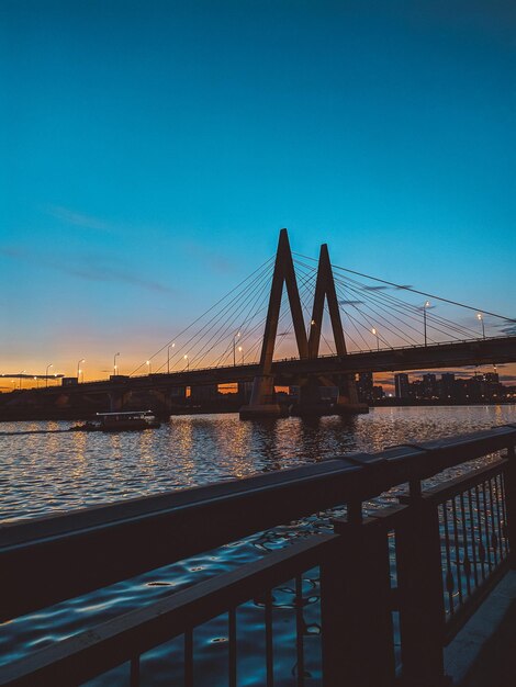 Suspension bridge over river against clear blue sky