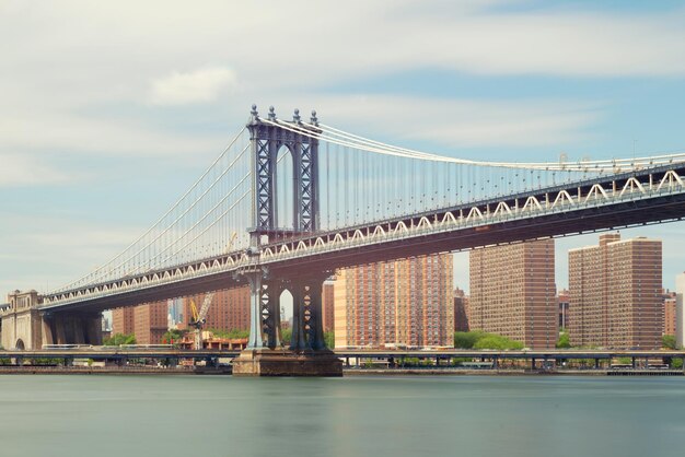 Suspension bridge over river against cloudy sky