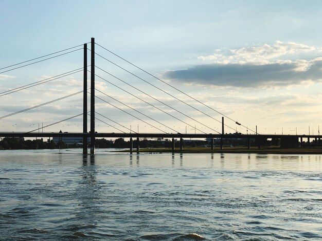 Suspension bridge over river against sky