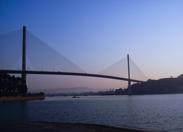 Suspension bridge over river against sky