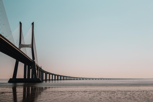 Suspension bridge over sea against clear sky