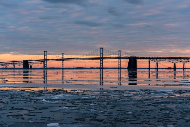 Suspension bridge over sea against sky during sunset