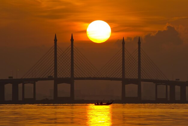 Photo suspension bridge over sea against sky during sunset