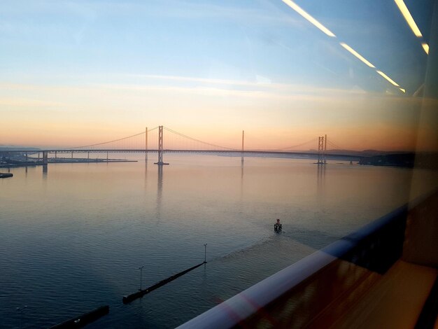 Photo suspension bridge over sea seen through glass against sky during sunset