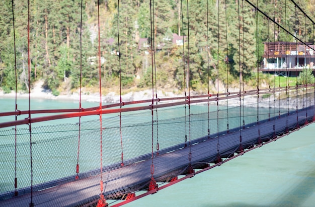 A suspension bridge over a wide river in the mountains. Safe crossing of the bridge from one bank to the other.