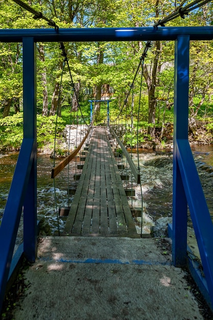 Suspension footbridge spans the river with waterfall Joaveski waterfall Estonia Baltic