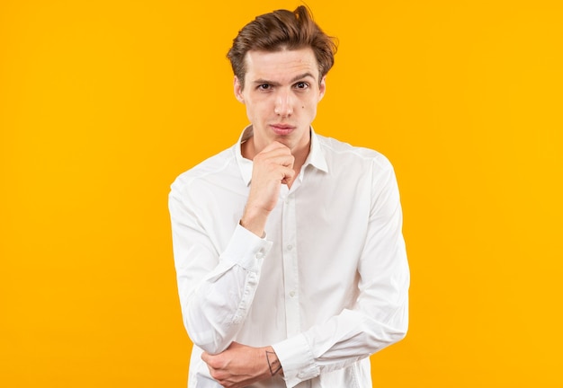 Suspicious young handsome guy wearing white shirt grabbed chin 