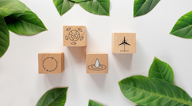 Photo sustainable resources symbols on wooden cube for renewal energy systems with leaves background