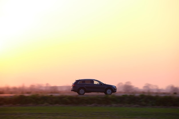 SUV-auto rijdt snel op intercityweg bij zonsondergang Snelwegverkeer in de avond