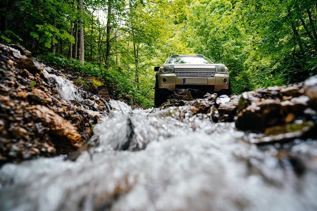 Foto auto suv da un ruscello che scorre attraverso le rocce nella foresta