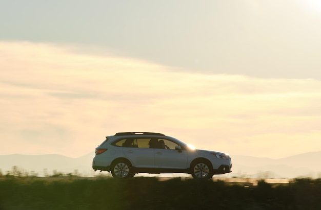 SUV car driving fast on intercity road at sunset. Highway traffic in evening.