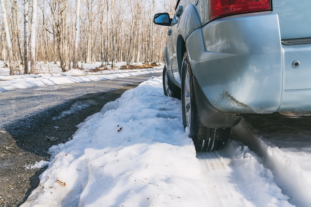 SUV car on snow covered asphalt road in forest