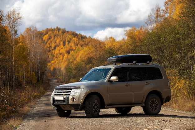 Photo suv on scenic autumn road in the forest