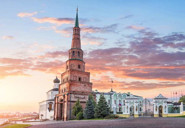 Suyumbike leaning tower in the kazan kremlin and the government\
building with a flag under a pink sunset sky