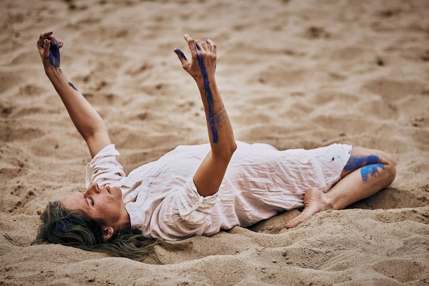 Svetlogorsk Russia 08152021  Female art dance performance on sandy beach Woman dancer lying on her back on sand and moving her hands at open air outdoor art performance Expressive slow dance