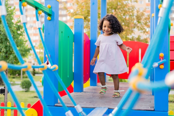 Photo swarthy baby with curly hair plays on a street playground the concept of a healthy lifestyle