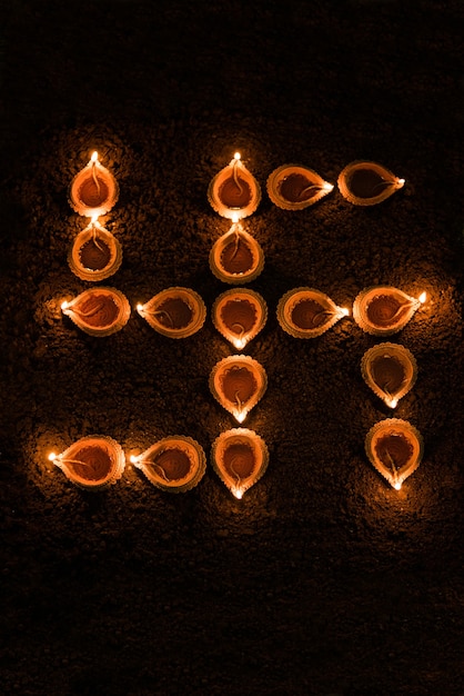 Photo swastika shape formed using diwali clay diya or oil lamps, selective focus