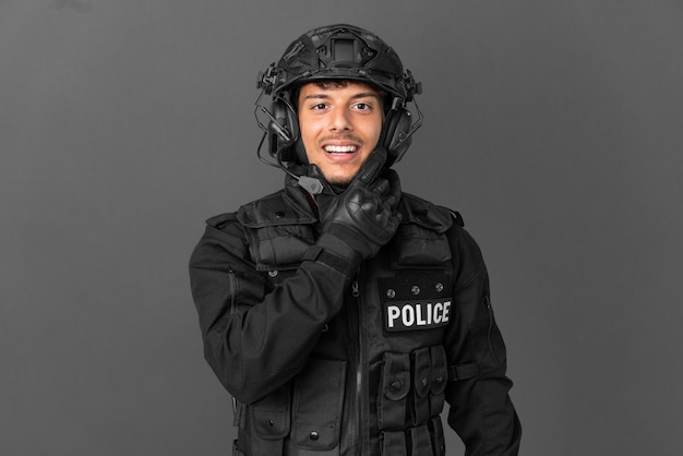 SWAT caucasian man isolated on grey background smiling