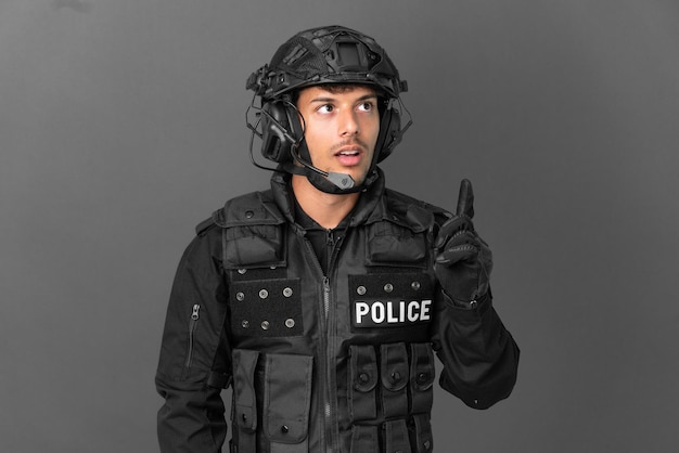 SWAT caucasian man isolated on grey background thinking an idea pointing the finger up