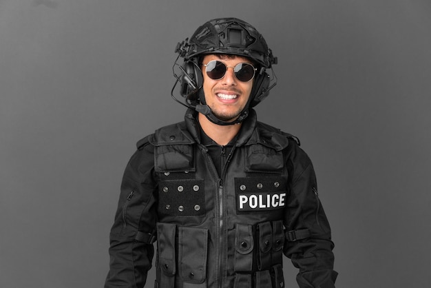 SWAT caucasian man isolated on grey background with glasses and happy