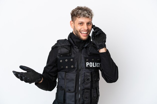 SWAT caucasian man isolated on white background keeping a conversation with the mobile phone with someone