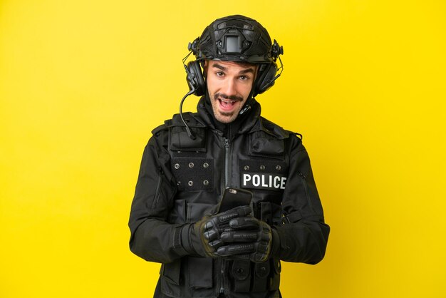 SWAT caucasian man isolated on yellow background surprised and sending a message