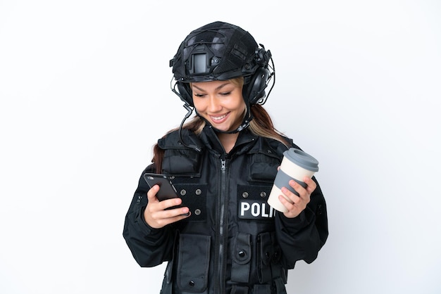 흰색 배경에 격리된 SWAT 러시아 여성은 테이크아웃 커피와 모바일을 들고 있습니다.