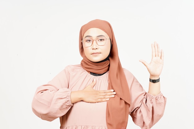 Клянущийся жест дает клятву красивой азиатской женщине в хиджабе, изолированной на белом фоне