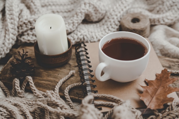 Foto maglioni e tazza di tè con notebook, candele e maglieria