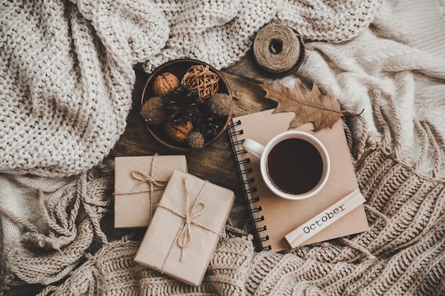 Sweaters and cup of tea with notebook, candle and knitting clothes