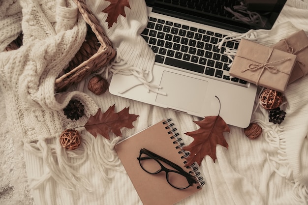 Sweaters and cup of tea with notebook, laptop and knitting clothes