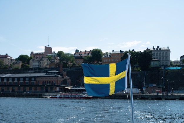 Sweden national flag waving blur waterfront Stockholm buildings and blue sky