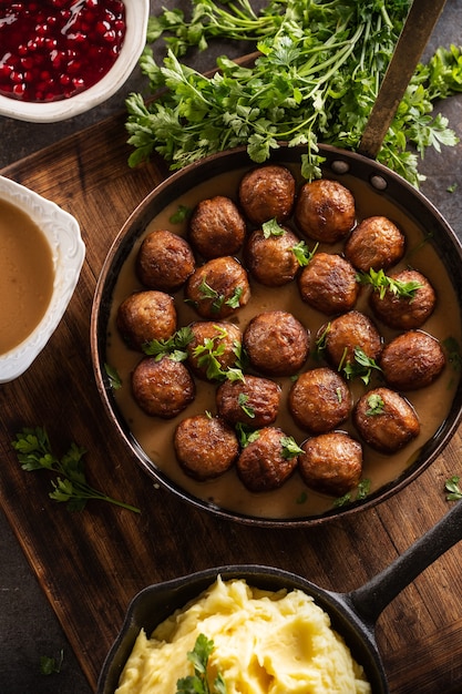 Swedish food Kottbullar meatballs, served in a pan with mashed potatoes, parsley and cranberry sauce.