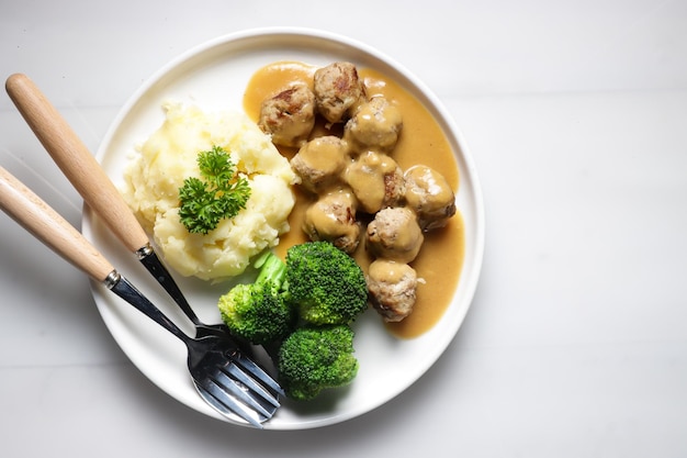 Swedish Meatball with brown mushroom sauce. Served on ceramic plate, on white table.