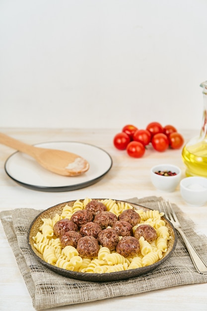 Swedish meatballs with fusilli paste on white wooden table