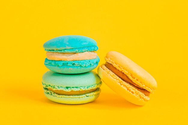 Mandorla dolce colorato unicorno macaron giallo blu o torta da dessert amaretto isolato su sfondo giallo alla moda moda moderna. biscotto dolce francese. concetto di panetteria alimentare minimale. copia spazio