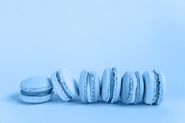 Sweet almond macaron or macaroon dessert cake colored in trendy color of year 2020 Classic Blue isolated on blue pastel background. Macro using color . copyspace.