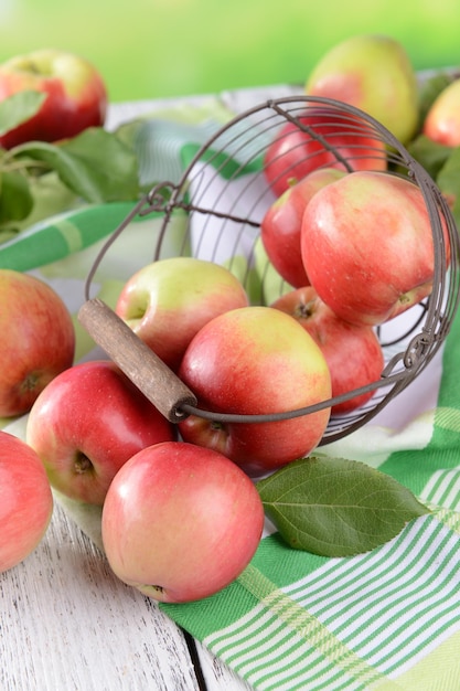 Sweet apples in wicker basket on table on bright background