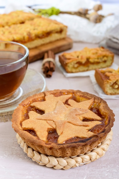 Sweet apricot cake - tartlet of pastry filled with jam and a cup of tea with cinnamon