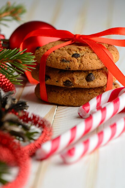 Sweet arrangement of striped candy canes and stack of delicious cookies wrapped with red ribbon.