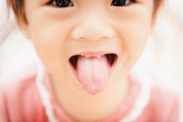 Sweet Asian child little girl brushing her teeth in bathroom 